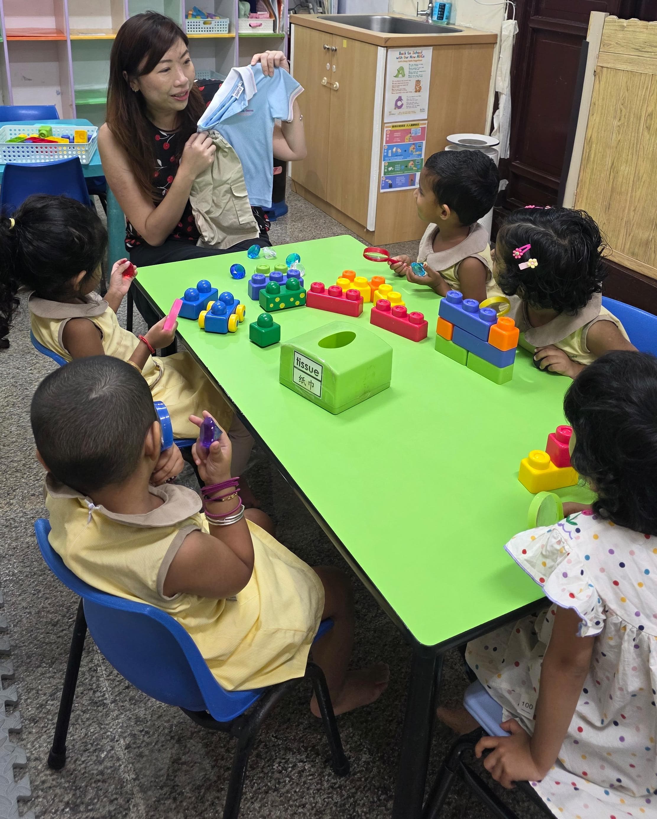 A qualified teacher at Genius Gems guiding a child during a hands-on learning activity in Changi